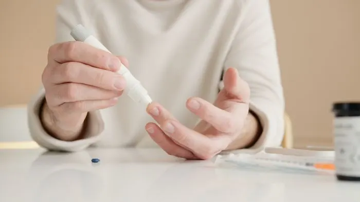 Person pricking a finger to check blood sugar with a lancet pen at home
